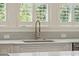 Modern kitchen sink with white cabinets, stainless steel fixtures, and natural light from the window at 337 Evian Way, Mount Pleasant, SC 29464