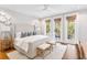 Bright bedroom featuring a large bed, white rug, and balcony access with nature views at 34 Eugenia Ave, Kiawah Island, SC 29455