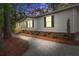 Charming single story home at dusk featuring a gravel yard and red brick accents, nestled in a wooded area at 409 Peacock Ln, Summerville, SC 29483