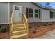 Close up of the home's entrance and front porch with wooden steps, red brick accents, and a freshly landscaped front yard at 409 Peacock Ln, Summerville, SC 29483