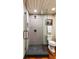 This bathroom features a tile shower with glass door, black shower floor and a toilet with an art piece hanging above at 6 Judith St, Charleston, SC 29403