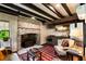 Cozy living room with a red patterned rug, exposed wood beam ceilings, brick fireplace, and charming vintage furnishings at 6 Judith St, Charleston, SC 29403
