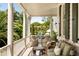 Inviting porch with wicker furniture, green cushions, columns, white railing and backyard view with patio seating at 6 Judith St, Charleston, SC 29403