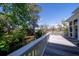 A wood deck with white railings overlooks lush greenery and mature trees at 8374 Chisolm Plantation Rd, Edisto Island, SC 29438