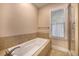 Bathroom features a soaking tub with tile surround, a window for natural light, and a glass shower door at 8409 Hidden Bakers Trce, North Charleston, SC 29418
