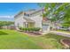 Two-story home with white siding, complemented by a manicured lawn, shrubs, and a tree-lined backyard at 9707 Seed St, Ladson, SC 29456