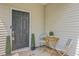 Close-up of a stylish black front door with a small outdoor table and greenery for a welcoming entrance at 9707 Seed St, Ladson, SC 29456