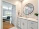 Bright bathroom featuring white cabinets, a round mirror, and marble countertops at 1025 Riverland Woods Pl # 106, Charleston, SC 29412