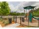 Community playground with play structure, swings, and play area enclosed by a fence at 114 W Bradford Pointe Dr, Summerville, SC 29483