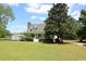 White two-story home with mature landscaping, featuring a large tree and storage shed at 18808 Round O Rd, Round O, SC 29474