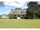 Quaint two-story home with red door, featuring a wide front yard with mature trees and a storage shed at 18808 Round O Rd, Round O, SC 29474