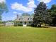 Quaint two-story home with a red front door, front porch, mature trees and a storage shed at 18808 Round O Rd, Round O, SC 29474