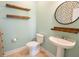 Charming powder room with pedestal sink, floating shelves, and decorative round mirror at 2107 Club View Ct, Charleston, SC 29412