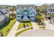 Aerial shot of blue two-story home with well-manicured lawn, palm trees, and a multi-car driveway leading to garage at 2107 Club View Ct, Charleston, SC 29412