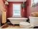 Vintage-style bathroom featuring a clawfoot tub, wood-paneled walls, and a bright window at 21785 Lowcountry Hwy, Ruffin, SC 29475