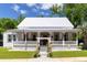 Charming two-story home featuring a metal roof, inviting porch, and manicured lawn, with American flag waving at 21785 Lowcountry Hwy, Ruffin, SC 29475