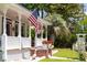 Charming front porch featuring classic white railings, a decorative pergola, and an American flag waving at 21785 Lowcountry Hwy, Ruffin, SC 29475