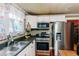 Kitchen with stainless steel appliances, black countertops, and colorful curtains at 21785 Lowcountry Hwy, Ruffin, SC 29475