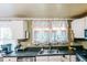 Bright kitchen featuring stainless steel appliances, black countertops and colorful curtains at 21785 Lowcountry Hwy, Ruffin, SC 29475