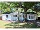 Charming white brick home featuring mature trees, a cozy front porch, and a freshly painted exterior at 227 Amy Dr, Goose Creek, SC 29445