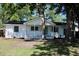 Exterior view of the freshly painted white brick home, complete with a charming covered porch and mature trees at 227 Amy Dr, Goose Creek, SC 29445