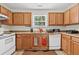 Well-lit kitchen featuring oak cabinets, tile floors, white appliances, and a window for natural light at 2919 Fernwood Dr, North Charleston, SC 29406