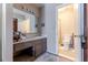 Bathroom with a gray vanity, sink, mirror, toiletries, a window, and a view of the toilet through the doorway at 4407 S Shirley Dr, North Charleston, SC 29418