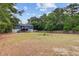 Large fenced backyard showcasing the house with back deck and stairs, surrounded by mature trees at 5669 Sands Rd, Hollywood, SC 29449