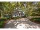 Quaint home with white siding and dark shutters surrounded by lush greenery and mature trees at 622 Venning St, McClellanville, SC 29458