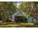 A quaint cottage with a screened porch nestled amongst mature trees and manicured landscaping at 622 Venning St, McClellanville, SC 29458