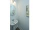 A half bath with a modern, round mirror above a pedestal sink and an abstract wall painting at 902 Twin Rivers Drive, Wando, SC 29492