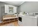Bright laundry room featuring a front load washer, dryer, bench, and window with white shutters at 1 Marlow Dr, Charleston, SC 29403