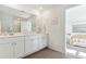 Bright bathroom featuring double sinks, white cabinetry, marble countertops, and access to bedroom at 1021 Swamp Rose Run, Summerville, SC 29485