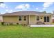 Back exterior showcasing a tan home with windows, sliding doors and a concrete patio overlooking a grassy yard at 112 Red Cypress Dr, Goose Creek, SC 29445