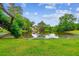 Serene pond surrounded by lush green grass, framed by mature trees and distant homes at 112 Red Cypress Dr, Goose Creek, SC 29445