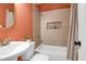Cozy bathroom featuring a shower/tub with light-colored tile, a single sink, and an orange-colored paneled wall at 1159 Camden St, North Charleston, SC 29405