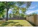 Large, grassy backyard enclosed by a wooden fence and mature trees, perfect for outdoor activities at 129 Mockernut Dr, Ladson, SC 29456