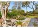 Lush backyard featuring a tranquil pond with stone edging, mature landscaping, and seating area at 1511 Fairway Dr, Charleston, SC 29412