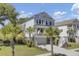 Stunning two-story coastal home featuring a charming front porch, driveway, and lush palm trees at 1513 Cultivation Ln, Mount Pleasant, SC 29466