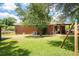 Spacious backyard with green lawn, brick home, covered patio, and a swing set for outdoor enjoyment at 1915 Aichele Dr, North Charleston, SC 29406