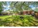 Lush backyard featuring a tire swing, playground set, and a charming brick home with a covered patio at 1915 Aichele Dr, North Charleston, SC 29406