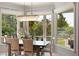 Bright dining area with chandelier, surrounded by windows showcasing water views and lush greenery at 1972 Long Creek Rd, Wadmalaw Island, SC 29487