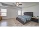 Spacious bedroom with a tray ceiling, ceiling fan, light wood-look floors, and two bright windows at 2113 Pimlico Dr, Ridgeville, SC 29472