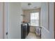 Bright laundry room features a modern washer and dryer, a window, shelving, and a convenient laundry basket at 2113 Pimlico Dr, Ridgeville, SC 29472