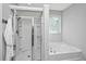Bright bathroom featuring a separate shower with glass doors and a soaking tub under a window at 2314 Hummingbird Ln, Summerville, SC 29483