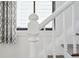Close up of a white staircase, with newel post, against a window and printed draperies at 272 Coming St # C, Charleston, SC 29403