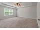 Spacious bedroom with neutral carpet, fan, and tray ceiling, illuminated by natural light from the large window at 296 Torslanda Ln, Summerville, SC 29486
