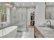 A modern bathroom features a soaking tub, glass shower, and marble accents, creating a luxurious spa-like retreat at 300 Ginned Cotton St, Charleston, SC 29492