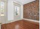 Bedroom with windows and exposed brick wall over hardwood floors at 35 Society St # D, Charleston, SC 29401
