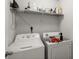 Functional laundry room with a washer, dryer, and storage shelf, perfect for household tasks at 5222 American Holly Ln, Ladson, SC 29456